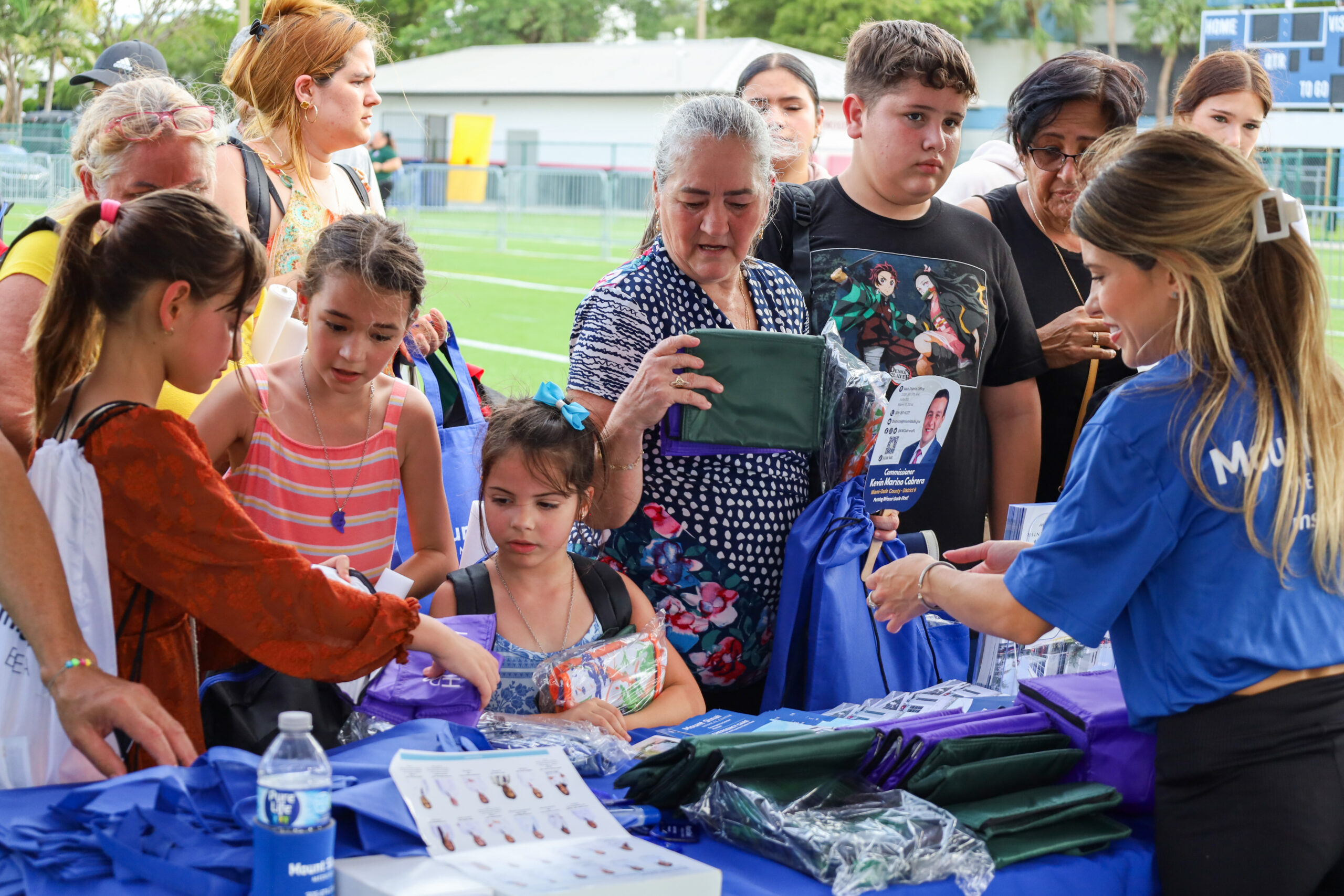 Picture of kids with their parents receiving school supplies from a sponsor.